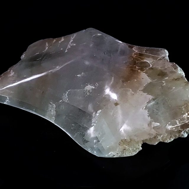 Crystal-clear selenite sculpture with gentle flowing curves, iron-rich earth inclusions, and calcium sulfate coral formations showcasing exceptional translucency and natural geometric clarity by Aaron K Metz