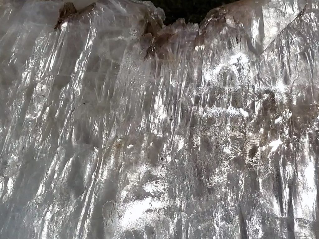 Clear selenite crystal specimen in laboratory setting demonstrating the mineral's characteristic fibrous structure and optical properties