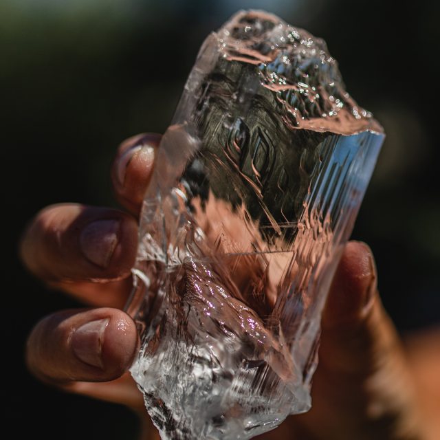 Hand holding a clear selenite ice crystal specimen showing perfect transparency and natural cleavage planes